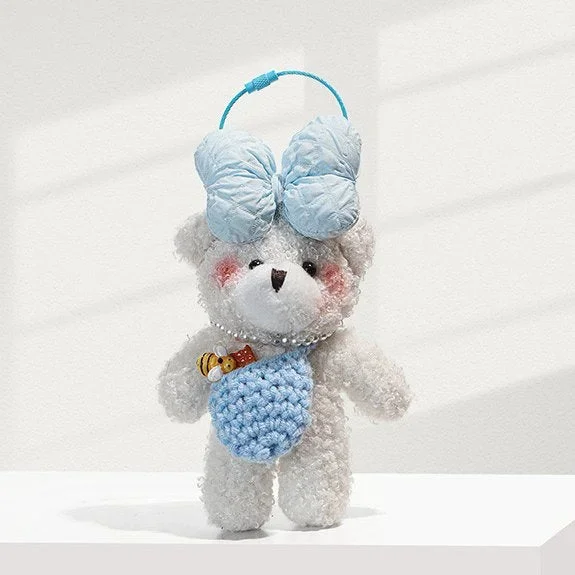 Bijou de sac ours en peluche blanc avec nœud bleu